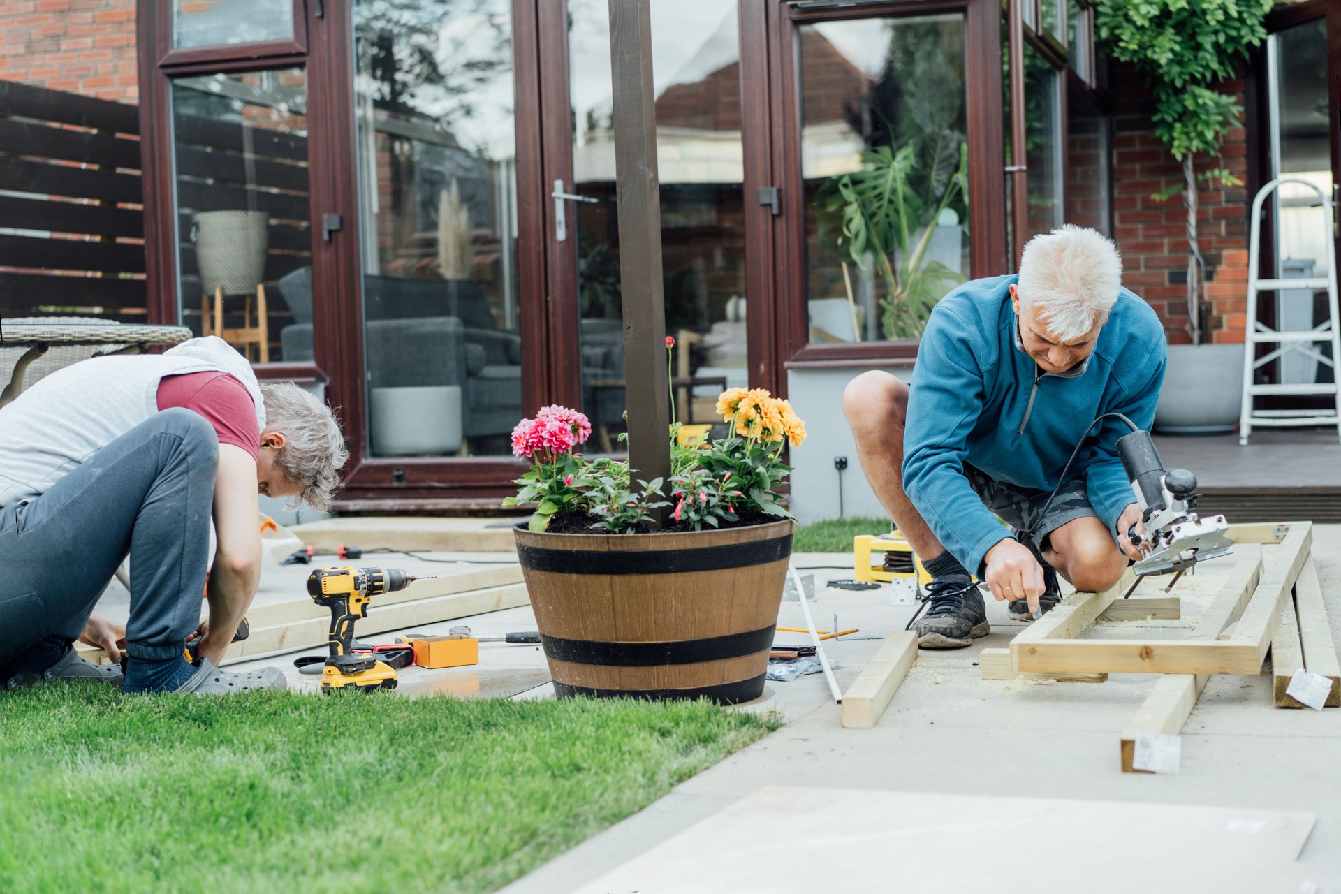 Adult son and father carpenter working together, handle wooden timbers in the garden. Patio construction by your own. DIY, Do it yourself. Home renovation, improvement, refurbishment. Selective focus